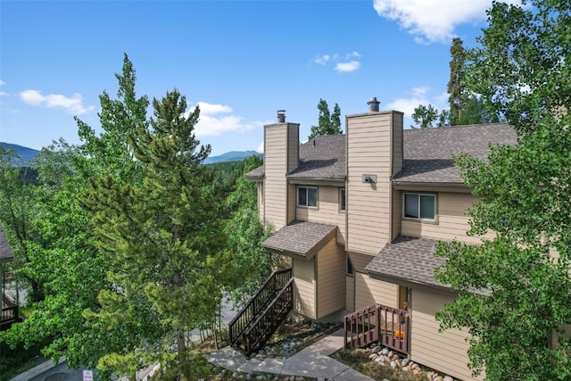 6941 Ryan Gulch Rd Unit 6941, Silverthorne, CO 80498 - back of house with stairway, a shingled roof, a chimney, and a mountain view