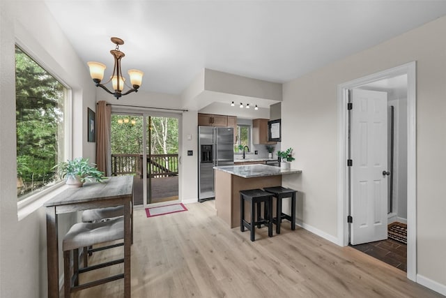 6941 Ryan Gulch Rd Unit 6941, Silverthorne, CO 80498 - kitchen featuring stainless steel refrigerator with ice dispenser, a peninsula, light wood-style flooring, a chandelier, and healthy amount of natural light