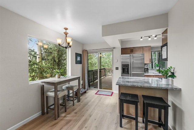 6941 Ryan Gulch Rd Unit 6941, Silverthorne, CO 80498 - kitchen with stainless steel refrigerator with ice dispenser, light wood-style flooring, a peninsula, track lighting, and a chandelier
