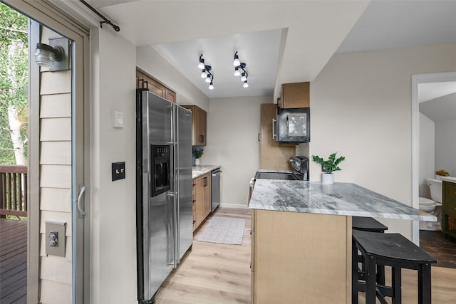 6941 Ryan Gulch Rd Unit 6941, Silverthorne, CO 80498 - kitchen featuring stainless steel appliances, a breakfast bar area, light wood-type flooring, a peninsula, and light stone counters