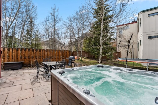 view of patio featuring a fenced backyard, a hot tub, and outdoor dining space