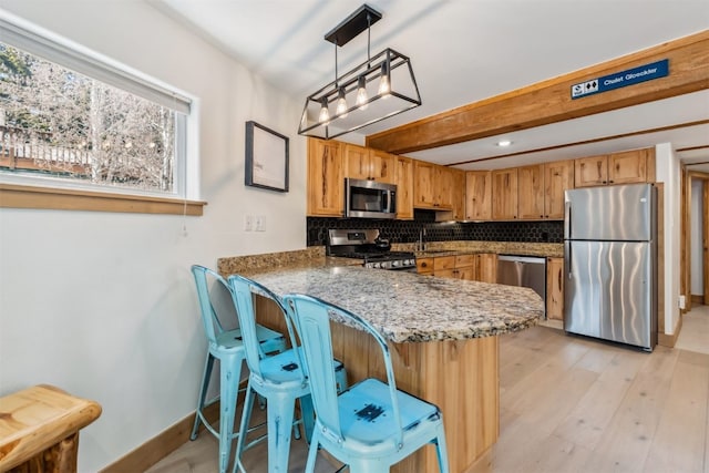 kitchen with tasteful backsplash, baseboards, light stone counters, a peninsula, and stainless steel appliances