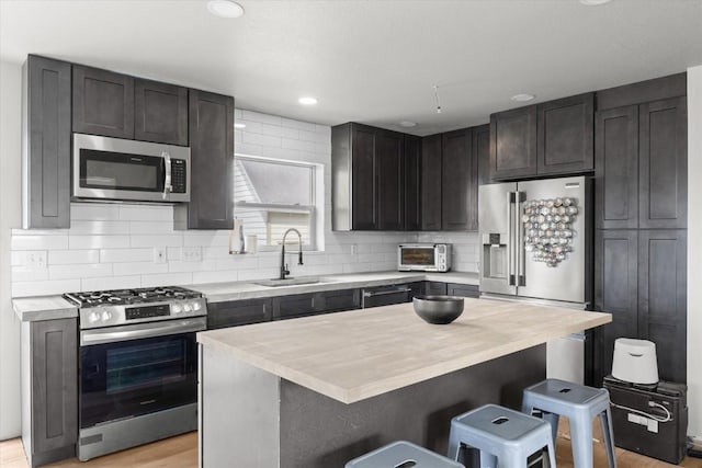 57680 Saturn Ct, Clark, CO 80428 - kitchen featuring stainless steel appliances, a sink, a breakfast bar area, decorative backsplash, and recessed lighting