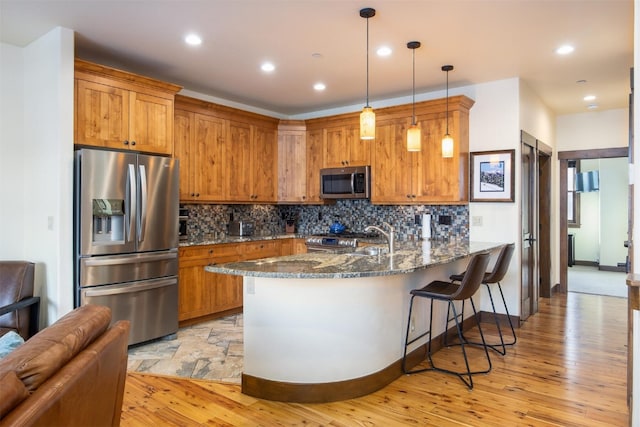 310 S 8th Ave Unit 4, Frisco, CO 80443 - kitchen with dark stone counters, brown cabinetry, light wood-style floors, a peninsula, and appliances with stainless steel finishes