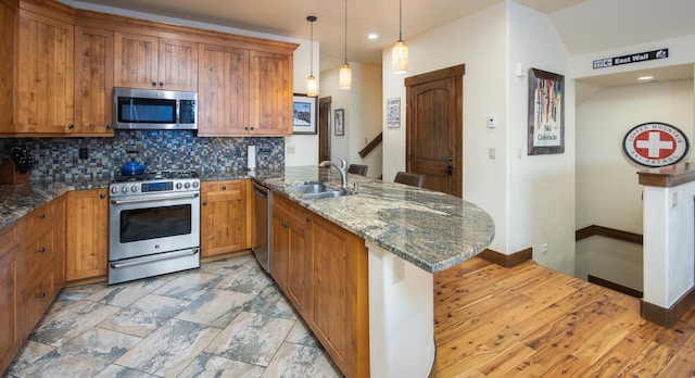 310 S 8th Ave Unit 4, Frisco, CO 80443 - kitchen featuring brown cabinets, a sink, a peninsula, tasteful backsplash, and appliances with stainless steel finishes
