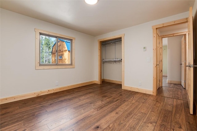 unfurnished bedroom with baseboards, wood finished floors, and a closet