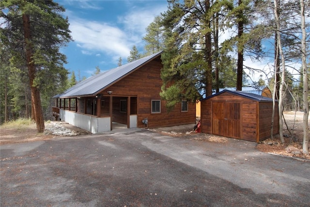 view of property exterior featuring an outdoor structure, a storage unit, and metal roof