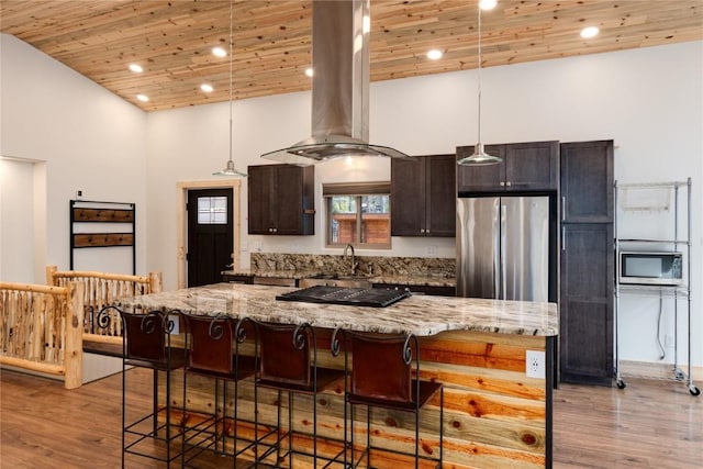 kitchen with a sink, island range hood, appliances with stainless steel finishes, wooden ceiling, and a breakfast bar area