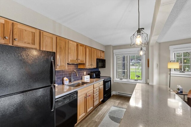 kitchen with light stone counters, a baseboard heating unit, black appliances, backsplash, and a sink