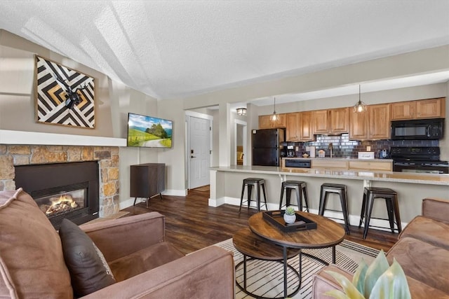 living room with dark wood finished floors, baseboards, a textured ceiling, and a fireplace