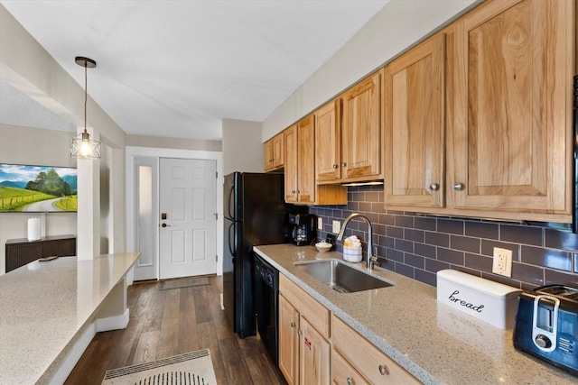 kitchen featuring black appliances, light stone counters, decorative backsplash, and a sink