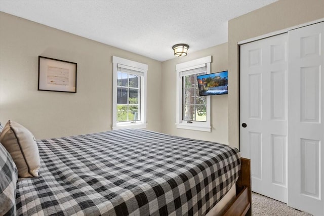 carpeted bedroom with a textured ceiling and a closet