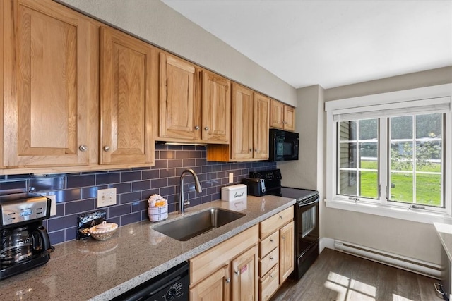 kitchen with decorative backsplash, a sink, baseboard heating, black appliances, and dark wood-type flooring
