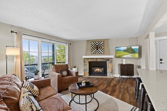 living room featuring a textured ceiling, baseboards, a fireplace, and dark wood-type flooring