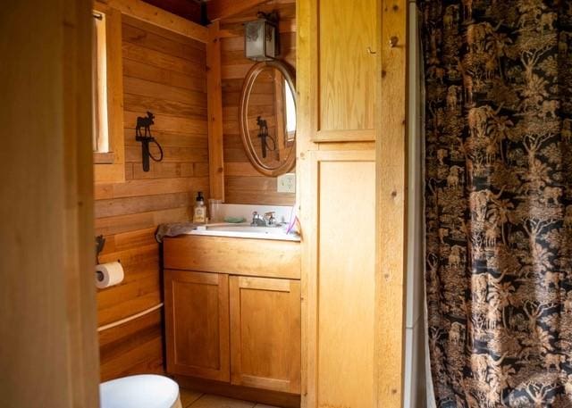 80 Sapling Ln, Craig, CO 81625 - bathroom with vanity, wooden walls, a shower with curtain, and tile patterned floors