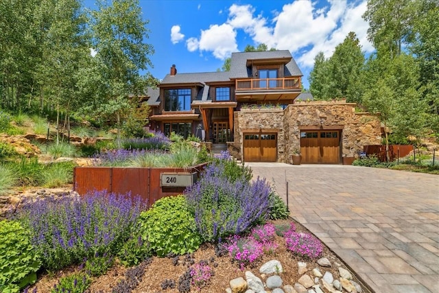 240 Two Cabins Dr, Silverthorne, CO 80498 - view of front facade featuring a balcony, stone siding, decorative driveway, a chimney, and an attached garage