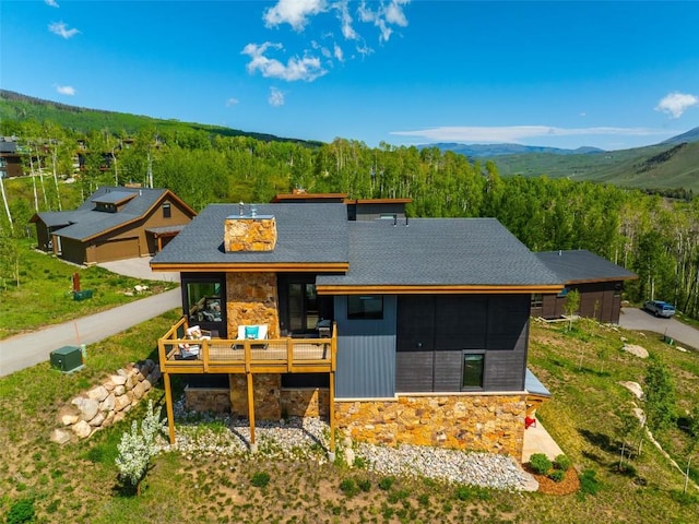 18 Lena Way, Silverthorne, CO 80498 - view of front of home with stone siding, a view of trees, a deck with mountain view, and a shingled roof