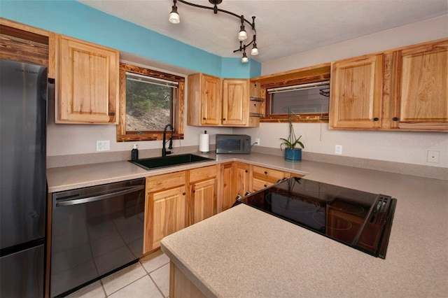 kitchen featuring light countertops, light brown cabinets, stainless steel appliances, and a sink