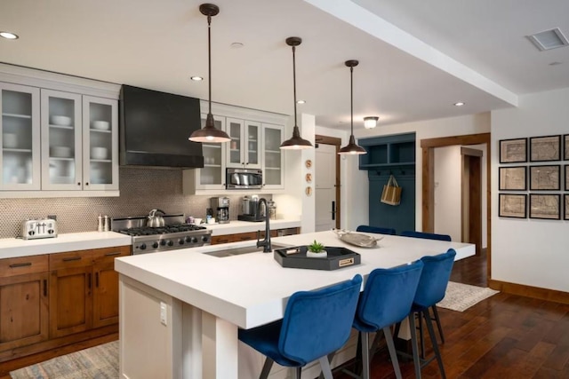kitchen featuring a sink, stainless steel microwave, extractor fan, brown cabinets, and range