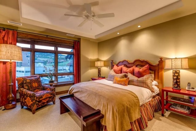 carpeted bedroom with a ceiling fan, a tray ceiling, visible vents, and recessed lighting