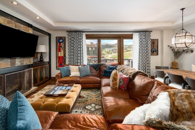 living area featuring recessed lighting, an inviting chandelier, a tray ceiling, and a fireplace