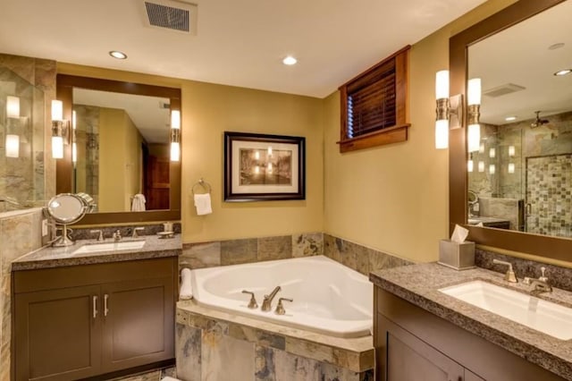 full bath with two vanities, a sink, visible vents, a shower stall, and a garden tub