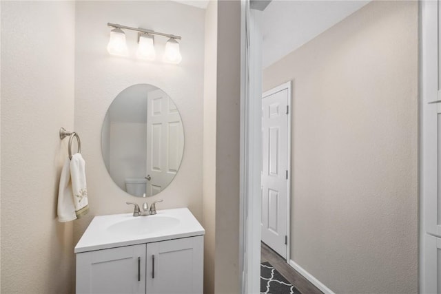 bathroom with baseboards, wood finished floors, and vanity