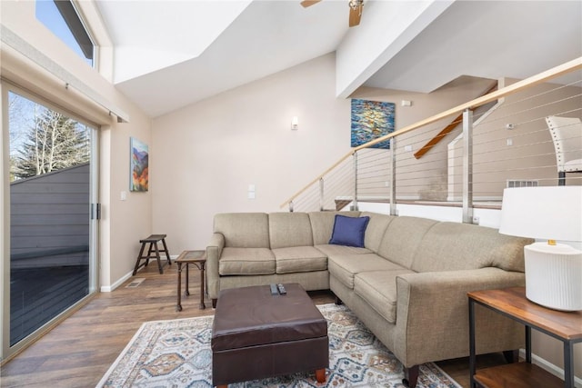 living area with stairway, wood finished floors, visible vents, a ceiling fan, and baseboards