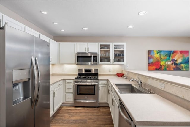 kitchen featuring white cabinets, a peninsula, a sink, light countertops, and appliances with stainless steel finishes