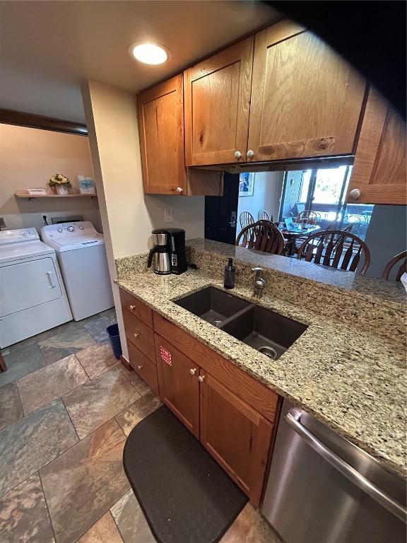 317 La Bonte St Unit 107, Dillon, CO 80435 - kitchen with dishwasher, washer and clothes dryer, brown cabinetry, and stone finish floors