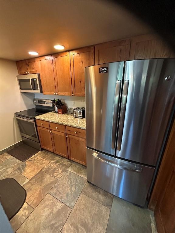 317 La Bonte St Unit 107, Dillon, CO 80435 - kitchen featuring stainless steel appliances, brown cabinetry, light stone counters, and recessed lighting