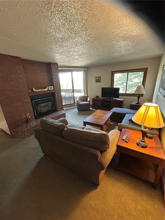 317 La Bonte St Unit 107, Dillon, CO 80435 - living area with carpet floors, a textured ceiling, plenty of natural light, and a brick fireplace