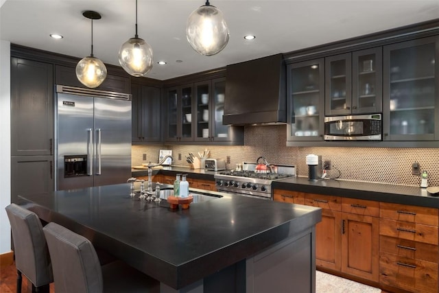 kitchen featuring dark countertops, custom exhaust hood, a sink, high end appliances, and backsplash