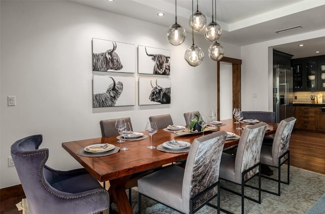 dining space with recessed lighting, dark wood finished floors, wet bar, and visible vents