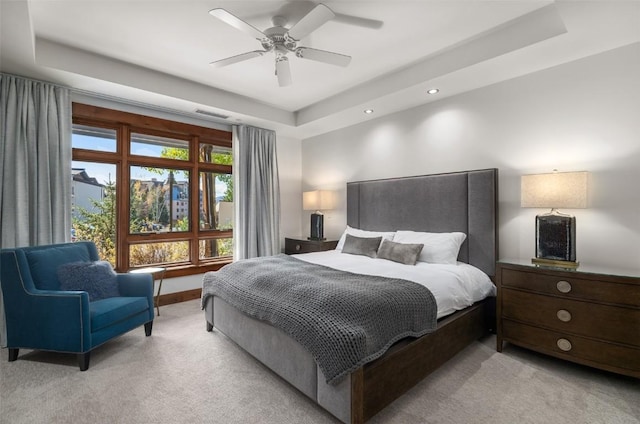 bedroom with a tray ceiling, visible vents, light colored carpet, and recessed lighting