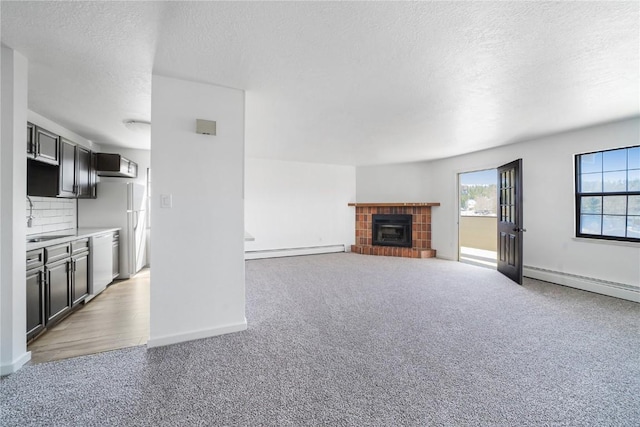 unfurnished living room with baseboards, a textured ceiling, baseboard heating, and light carpet
