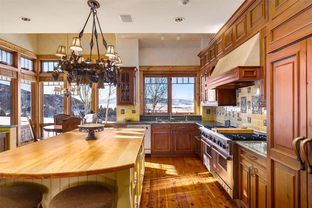 33800 Catamount Dr, Steamboat Springs, CO 80487 - kitchen with stainless steel appliances, wood counters, a chandelier, custom exhaust hood, and hardwood / wood-style flooring