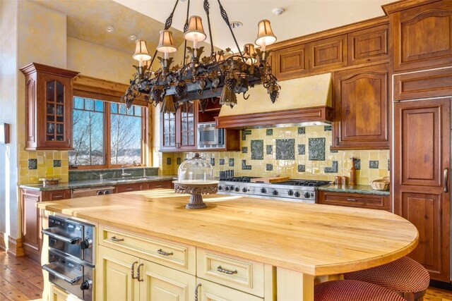 33800 Catamount Dr, Steamboat Springs, CO 80487 - kitchen with butcher block counters, a chandelier, decorative backsplash, and glass insert cabinets