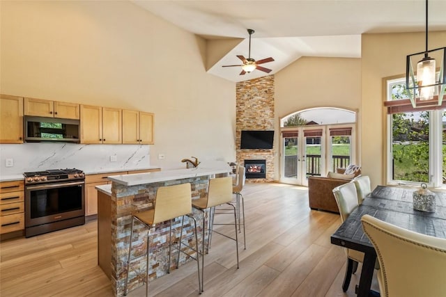 620 Parkview Dr Unit 61, Steamboat Springs, CO 80487 - kitchen featuring appliances with stainless steel finishes, light brown cabinetry, high vaulted ceiling, open floor plan, and a ceiling fan