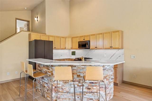 620 Parkview Dr Unit 61, Steamboat Springs, CO 80487 - kitchen with stainless steel appliances, light brown cabinetry, light wood-style floors, light countertops, and high vaulted ceiling