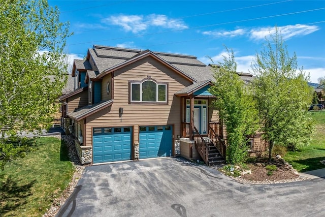 620 Parkview Dr Unit 61, Steamboat Springs, CO 80487 - view of front of house featuring driveway, a garage, stone siding, and roof with shingles