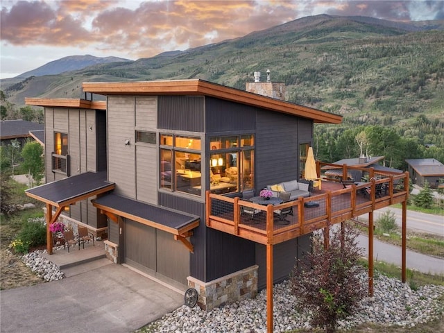 22 Vernon Way, Silverthorne, CO 80498 - rear view of property with a chimney, an attached garage, driveway, a deck with mountain view, and an outdoor hangout area