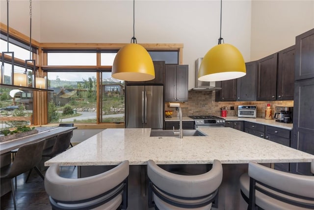 22 Vernon Way, Silverthorne, CO 80498 - kitchen featuring stainless steel appliances, wall chimney exhaust hood, a high ceiling, dark brown cabinets, and decorative backsplash