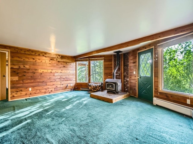 134 Hideaway Ct, Dillon, CO 80435 - unfurnished living room with a wood stove, wooden walls, healthy amount of natural light, a baseboard radiator, and carpet floors