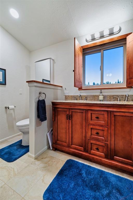 726 Cumberland Dr, Jefferson, CO 80456 - bathroom featuring double vanity, toilet, baseboards, and a sink