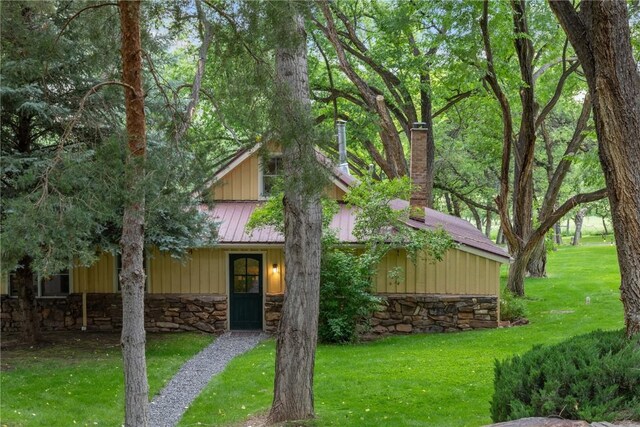 34074 Fruitland Mesa Rd, Crawford, CO 81415 - view of front of house with a chimney, a front lawn, a standing seam roof, stone siding, and metal roof