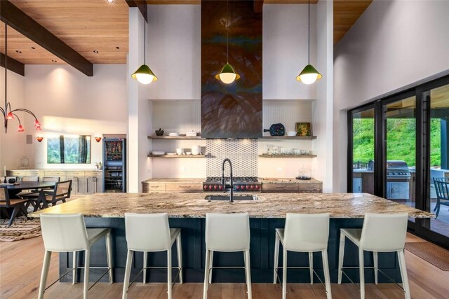 33200 Meadow Creek Dr, Steamboat Springs, CO 80487 - kitchen with a high ceiling, open shelves, a wooden ceiling with exposed beams, light stone counters, and light wood finished floors