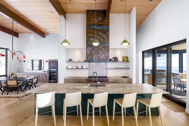 33200 Meadow Creek Dr, Steamboat Springs, CO 80487 - kitchen with a wood ceiling with exposed beams, light wood finished floors, a high ceiling, light stone countertops, and decorative light fixtures