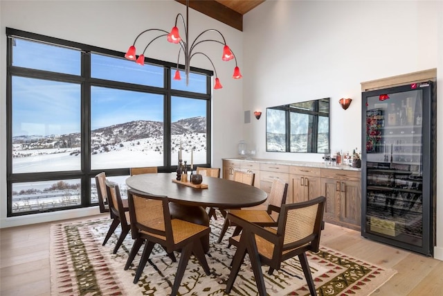 33200 Meadow Creek Dr, Steamboat Springs, CO 80487 - dining room featuring wine cooler, light wood-type flooring, a high ceiling, a mountain view, and beam ceiling