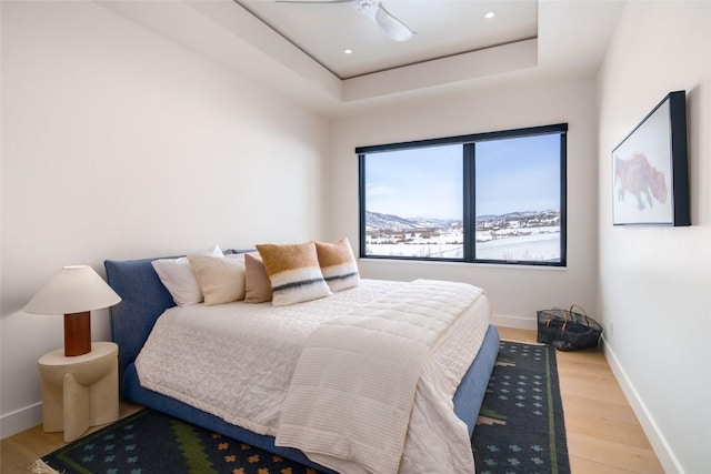 33200 Meadow Creek Dr, Steamboat Springs, CO 80487 - bedroom with light wood-style floors, a tray ceiling, and a ceiling fan